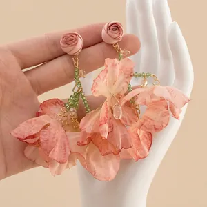 Detail of handmade fabric flower earrings with pink petals and green beaded stems