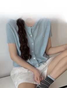 Detail of light blue striped knit cardigan featuring a round neck and single-breasted buttons