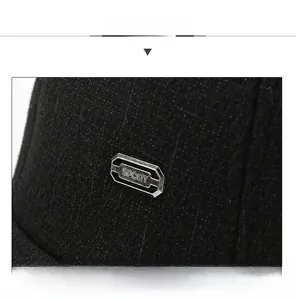 Detail of black twill baseball cap fabric with a silver metal SPORT logo plate