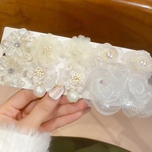 Macro shot of white fabric flower and pearl earring set on display card with lace details