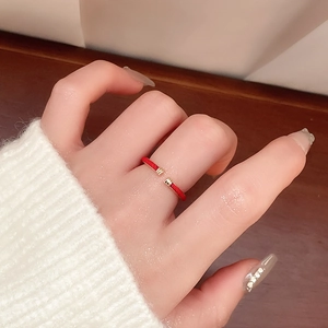 Detail of red snake-shaped open ring on model with white knit sweater and wooden backdrop