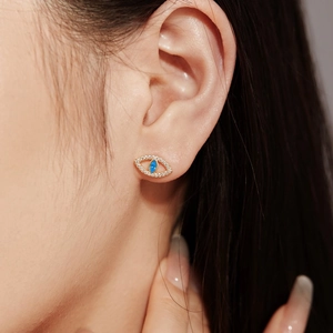 Détail du clou d'oreille mauvais œil en argent S925 doré porté sur le lobe d'oreille