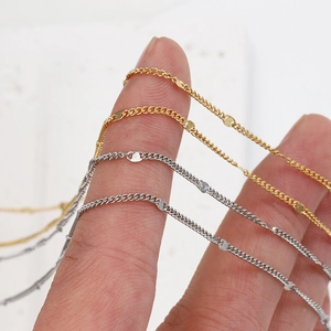 Polished 18k gold and silver stainless steel link chains held on fingertips for scale