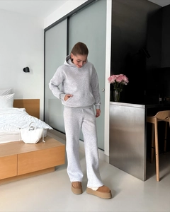 Women's grey tracksuit detail showing hooded sweatshirt and loose pants in home setting