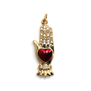Close-up of golden palm pendant with a red heart enamel and sparkling crystals