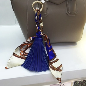 Ciondolo per borsa con nappa in pelle blu scuro e sciarpa di seta su borsa beige