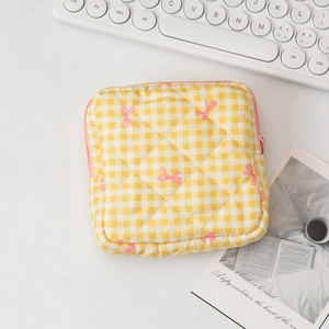 Detailed close-up of quilted yellow checkered makeup bag with pink bow pattern and zipper