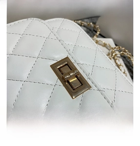 Dettaglio della pelle trapuntata bianca e della chiusura girevole dorata su borsa mini