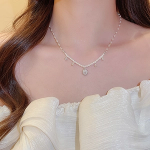 Close-up of pearl necklace with a silver floral pendant featuring sparkling zircons on a model