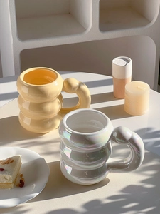 Detail view of two bubble-shaped ceramic mugs in cream yellow and aurora white colors