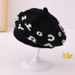 Detail view of black knit beret for children featuring white jacquard letter patterns