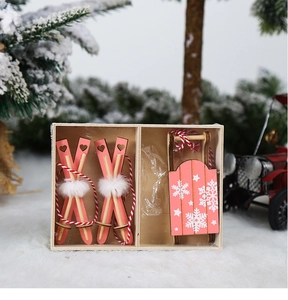 Detail view of pink wooden sled and skis ornaments with heart cutouts in a wooden gift box