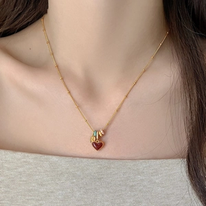 Close-up of 18k gold plated necklace with a red heart pendant worn by a model