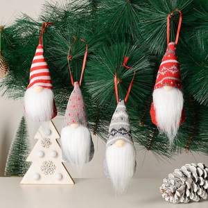 Set of four knitted Christmas gnomes hanging on pine branches with snowy holiday decor