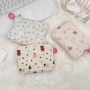 Detail of quilted cosmetic pouches featuring floral, bear and rabbit patterns on white rug