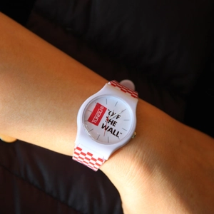 Close-up of a white silicone watch strap with a red checkerboard pattern and logo