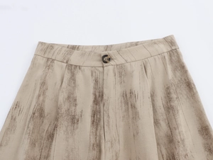 Dettaglio ravvicinato della vita dei pantaloni beige con stampe astratte e pieghe