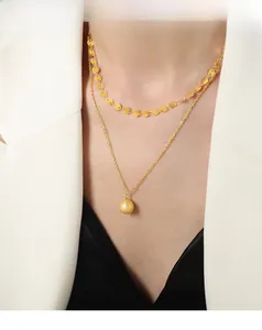 Close-up of double layer gold necklace featuring a matte sphere pendant and sequin chain