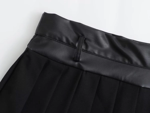 Detail shot of the black pleated skort waist featuring faux leather and fabric patchwork