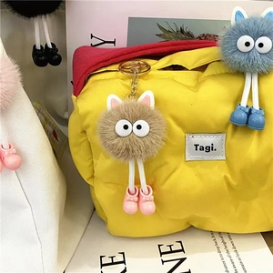 Quilted yellow puffy tote bag featuring cartoon soot sprite plush charms and brand logo tag
