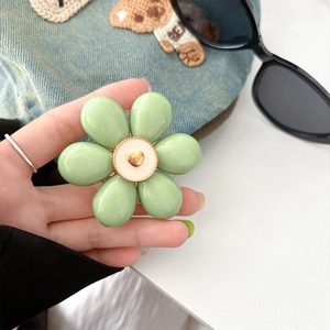 Detailed view of a light green flower phone stand with a golden heart center on denim