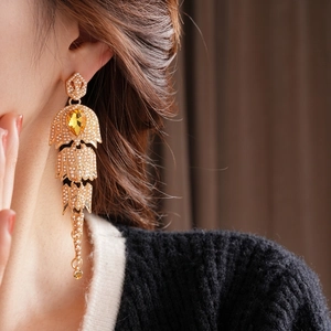 Vintage gold drop earrings with tiered pearls and a yellow teardrop gemstone on a model