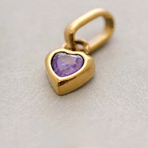 Macro shot of gold heart pendant with purple amethyst stone and February engraving