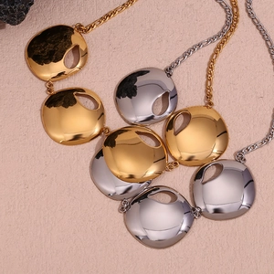 Top view of gold and silver circular cutout necklaces on a beige textured background