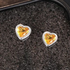 Macro shot of silver heart earrings with vibrant yellow zircon and high luster