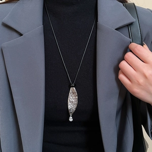 Detail of silver leaf pendant with hammer texture and crystal drop on a black cord
