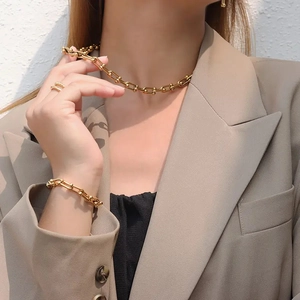 Gros plan sur collier et bracelet à maillons en U dorés portés par un mannequin