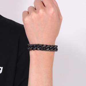 Détail du bracelet gourmette en acier inoxydable noir sur le poignet d'un homme