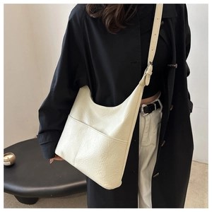 Close-up of cream leather tote bag featuring pleated texture on a shoulder strap