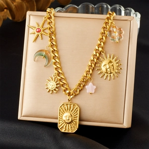Detail of gold chain necklace with celestial sun, moon and star charms on a display stand