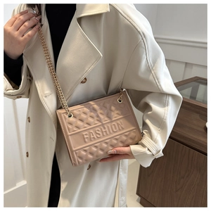 Detail of beige quilted shoulder bag with metal chain strap and embossed fashion text