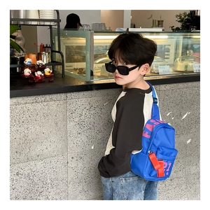 Gros plan d'un sac bandoulière bleu pour enfant en toile avec texte rose et boucle orange