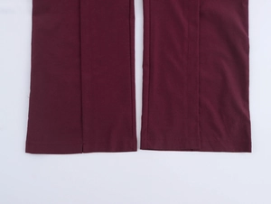 Close-up of burgundy high-waist straight trousers featuring split hem and woven fabric