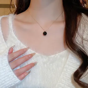 Elegant gold necklace with a black pearl pendant and zircon accents on a model's neck