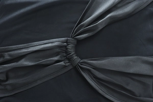 Detail shot of black dress showing mesh patchwork, twisted knot design and stitching