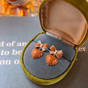 Elegante goldene Schleifenohrringe mit orangefarbenem Herz und Perlen in Samtbox