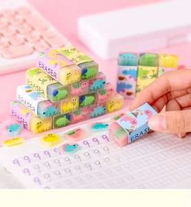 Close-up of colorful cartoon dinosaur jelly erasers on a pink desk with a notebook
