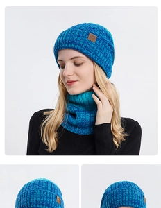 Detail van gebreide wintermuts en sjaalset in meerblauw met sportief lederen logo-label