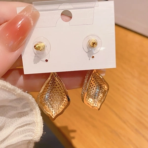 Détail de boucles d'oreilles dorées en forme de goutte avec dos alvéolé et zircons brillants