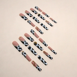 French cow print press-on nails with gold edges and rhinestones in coffin shape