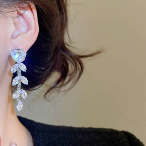 Detailed close-up of zircon flower tassel earrings with shimmering leaf crystals on model