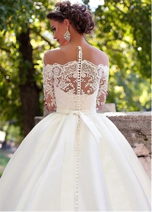 Exquisite back detail of white lace wedding dress with delicate buttons and satin bow