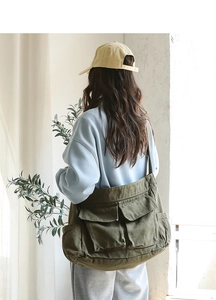 Detailed view of the army green large canvas messenger bag worn by a model