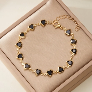Elegant gold heart chain bracelet with black stone inserts in a luxury jewelry box
