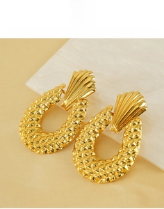 Macro detail of gold geometric hoop earrings with textured diamond pattern on silk