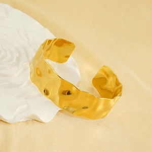 Close-up of golden 18K plated cuff bracelet with unique wavy hammered texture detail
